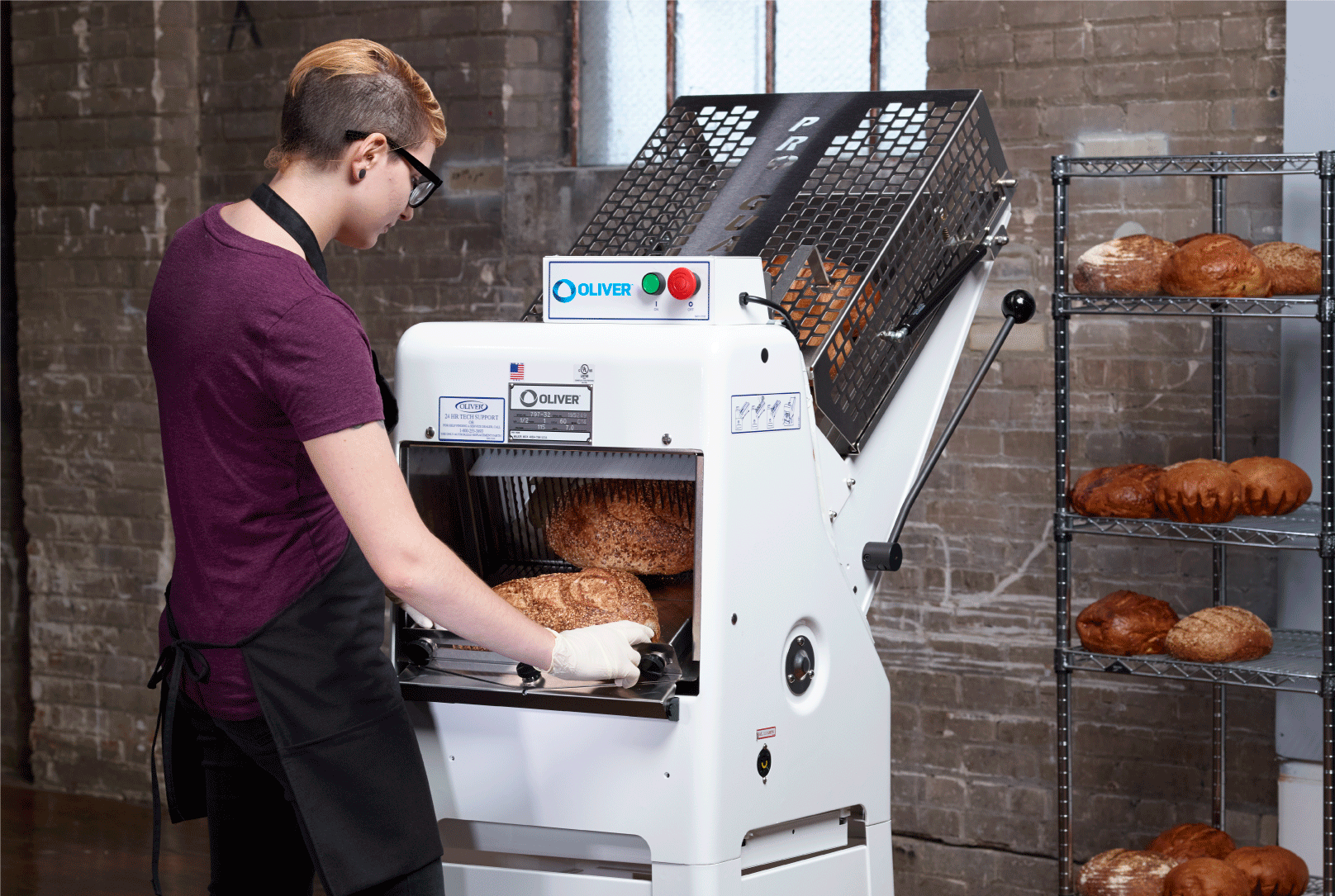 Baker slicing loaves of bread using the Oliver Gravity Feed Bread Slicer