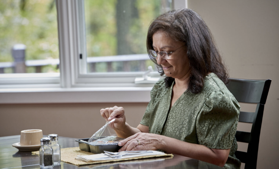A woman opens a senior meal sealed with Oliver’s food packaging solutions